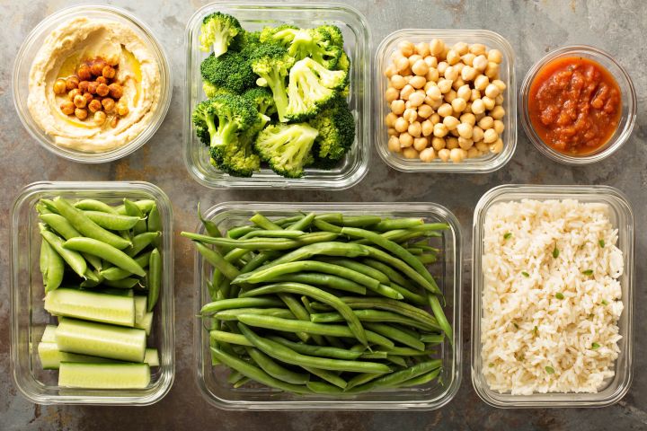 Vegetarian meal planning with containers of hummus, vegetables, chickpeas, and rice.