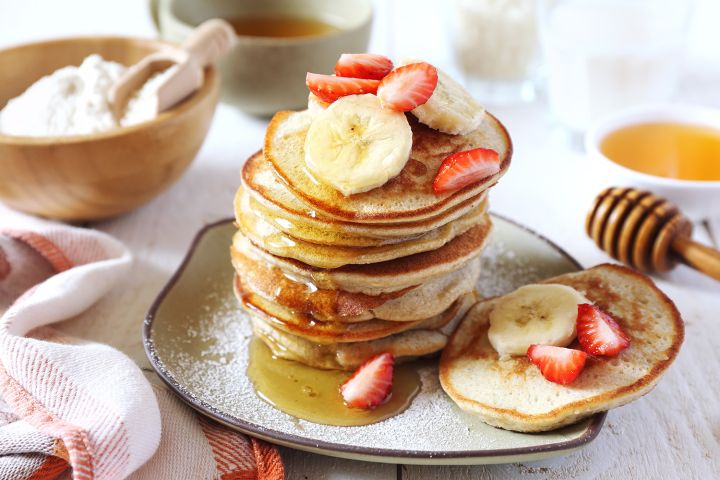Banana and egg pancakes with maple syrup and sliced bananas.