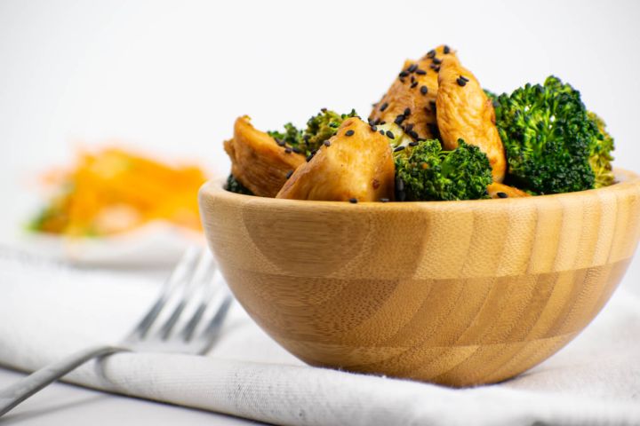 Chicken broccoli stir fry with stir fry sauce in a wooden bowl with sesame seeds.