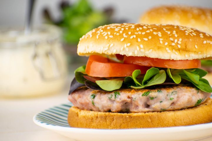 Chicken caesar burger with lettuce and tomato on a bun.