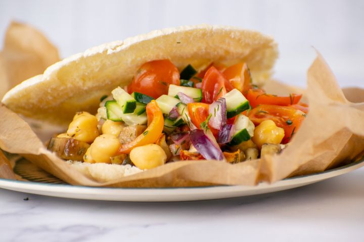 Greek tostadas with chickpeas, eggplant, tomatoes, red onions, and cucumbers on toasted pita bread.