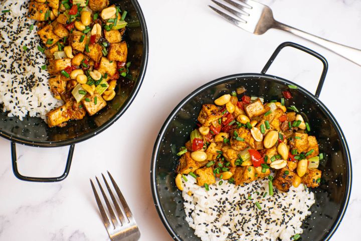 Kung Pao Tofu with celery, red peppers, and peanuts in a dish with white rice.