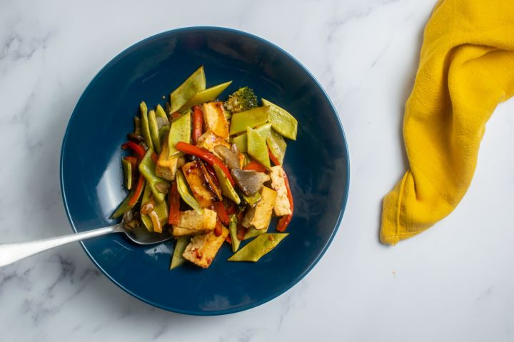Sheet pan asian tofu with vegetables in a blue bowl with a yellow napkin.