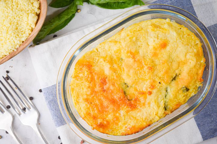 Spaghetti squash gratin in a glass baking dish with parmesan cheese and basil.