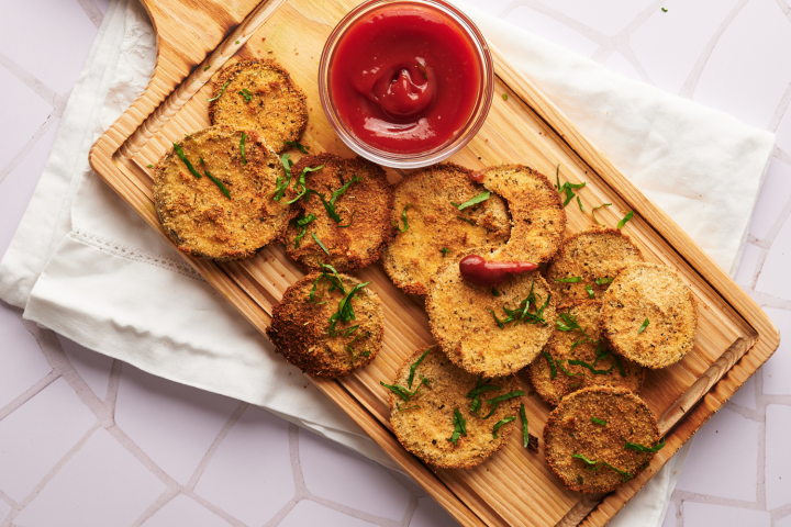 Eggplant cutlets coated in breadcrumbs on a plate with fresh herbs.