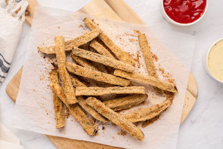 Baked eggplant fries with a crispy Parmesan and breadcrumb coating on a plate with ketchup.