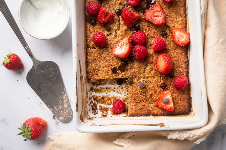 Baked oatmeal made with rolled oats in a baking dish with raspberries, strawberries, and chocolate chips.