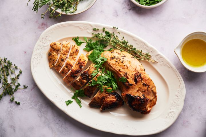 Baked turkey tenderloin sliced on a plate with fresh herbs.