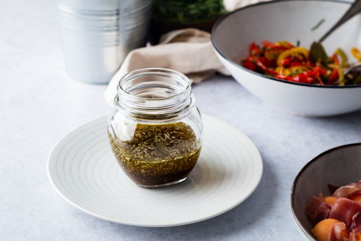 Balsamic grilled vegetable marinade in a glass jar with grilled vegetables on the side. 