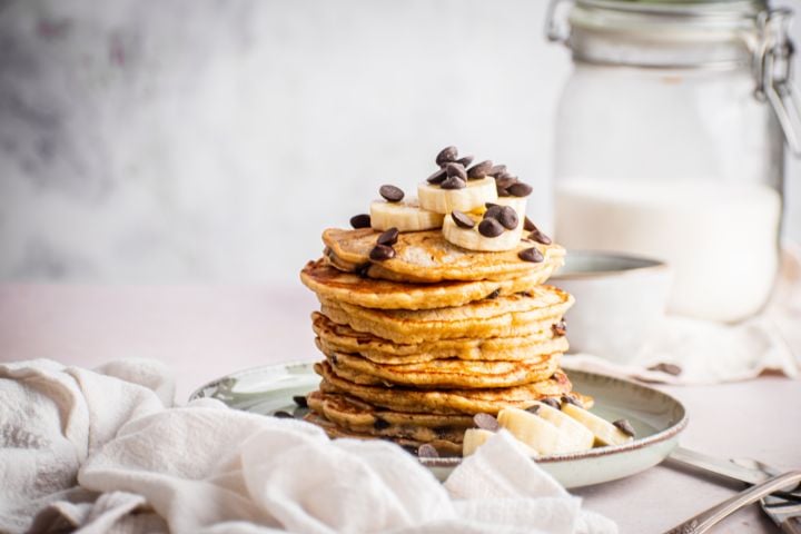 Banana chocolate chip pancakes on a plate and served with whipped cream.