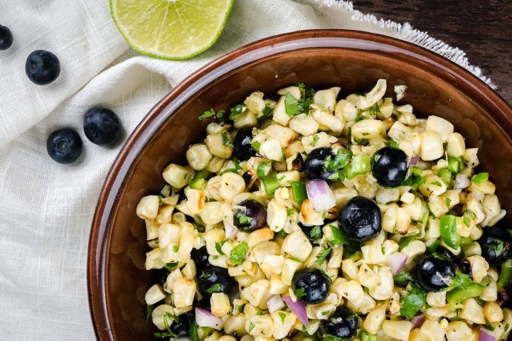 Blueberry corn salad with red onions and herbs in a bowl.