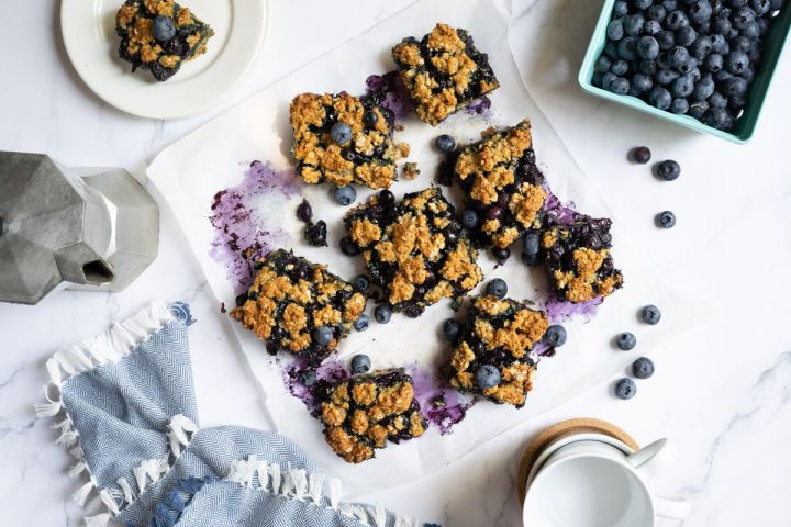 Blueberry oat bars with roasted blueberries and a oatmeal crumb topping cut into squares.