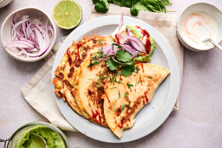 Buffalo chicken quesadillas cut into triangles with buffalo sauce drizzled on top.