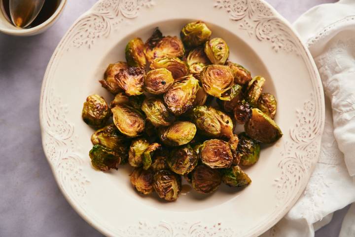 Caramelized Brussels sprouts with browned, crispy edges in a bowl with honey balsamic galze.