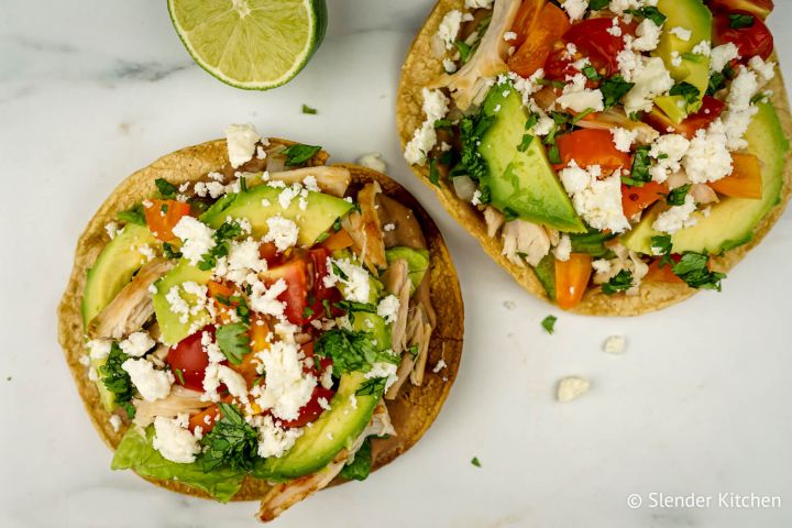 Chicken tostadas with refried beans, chicken, lettuce, salsa, cheese, and cilantro.