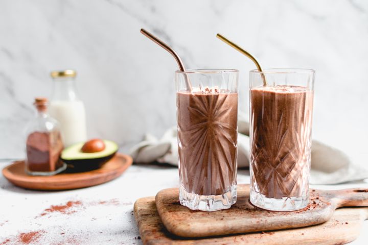 Chocolate avocado smoothie in a glass with blended avocado, banana, cocoa powder, chia seeds, and more.