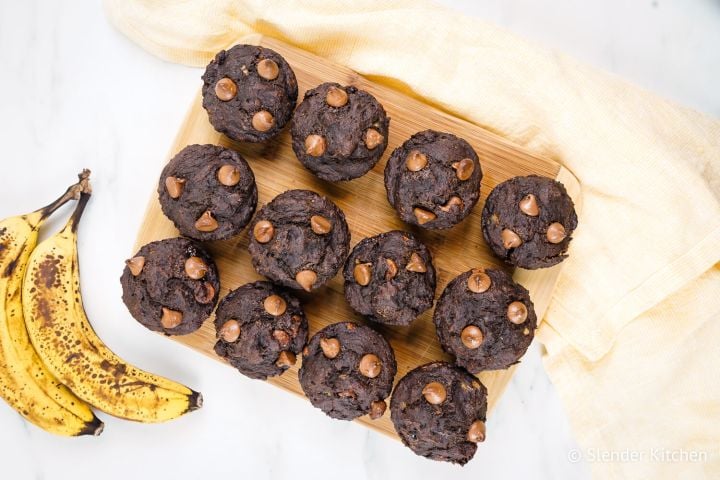 Chocolate banana muffins made with ripe bananas on a wooden board with chocolate chips.