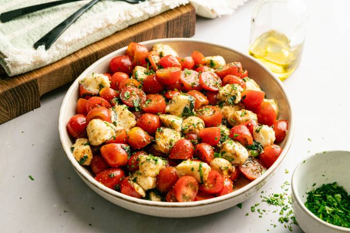 Overhead view of chopped Caprese salad made with juicy cherry tomatoes, mozzarella, fresh basil, olive oil, and balsamic glaze.