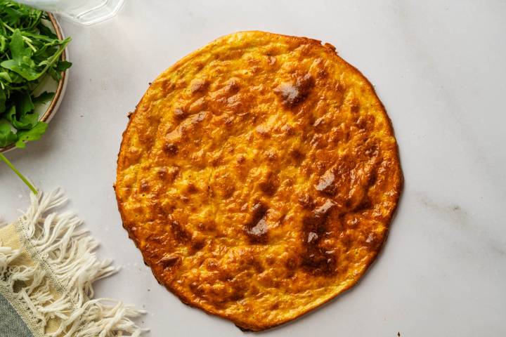 Baked cottage cheese flatbread on a countertop, showing its golden brown color and lightly crisp edges.