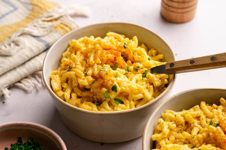 Close-up of a bowl of creamy homemade high protein mac and cheese garnished with paprika and chopped parsley.