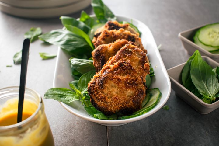 Crispy almond crusted pork chops with almond meal on a bed of greens with mustard sauce on the side.