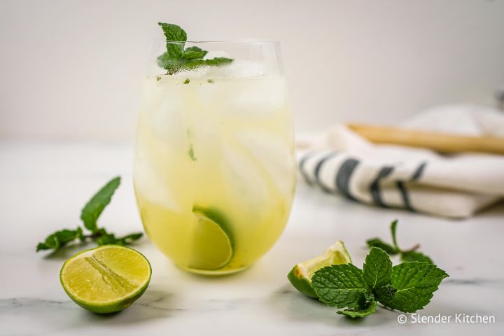 Mojito with fresh mint, lime juice, and rum in a glass with lime and mint on the side.