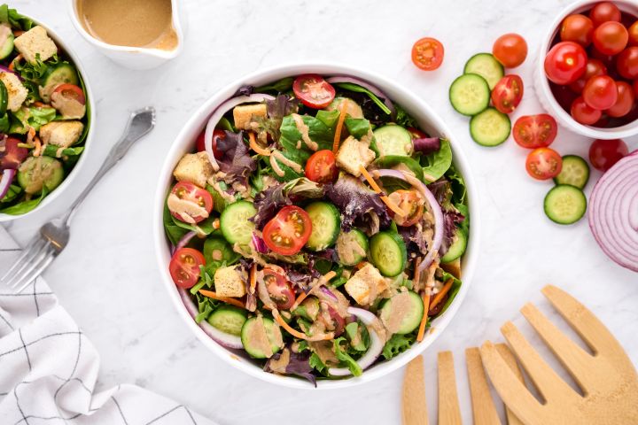 Spring mix salad in a bowl with various lettuce, cucumbers, tomatoes, and balsamic dressing.