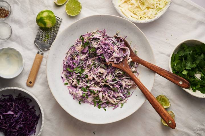 Fish taco slaw in a bowl with shredded cabbage, cilantro, lime juice, and green onions in a bowl.