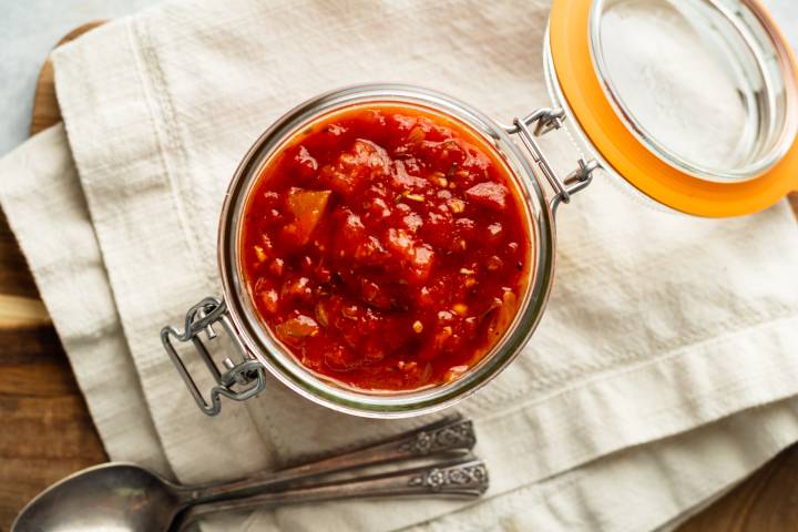 Fra diavolo sauce with tomatoes, chile flakes, garlic, onion, and spices in a glass jar. 