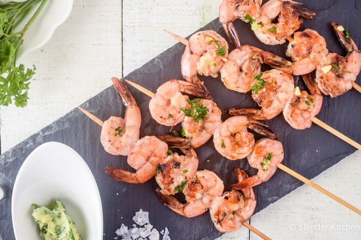 Garlic lemon shrimp kabobs on a piece of slate with garlic and parsley.