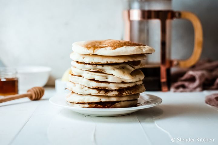 Greek yogurt stacked on a plate with maple syrup and coffee on the side.