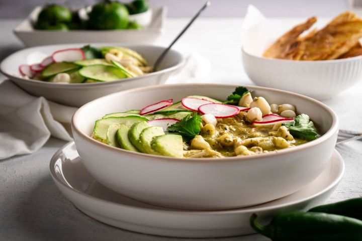 Green pozole with shredded chicken, hominy, cilantro, and avocado in a bowl.