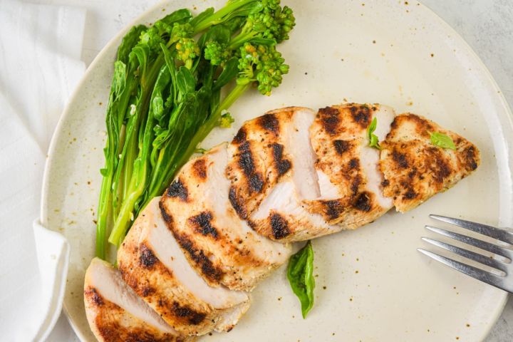 Grilled basil lime chicken breast with fresh basil, lime juice, lime zest, and broccoli on the side.