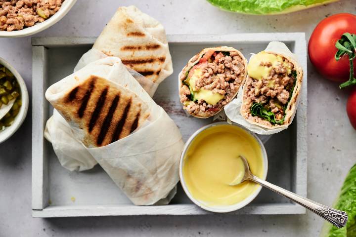 Cheeseburger wraps in a tortilla with ground beef, lettuce, and tomatoes served with homemade burger sauce.