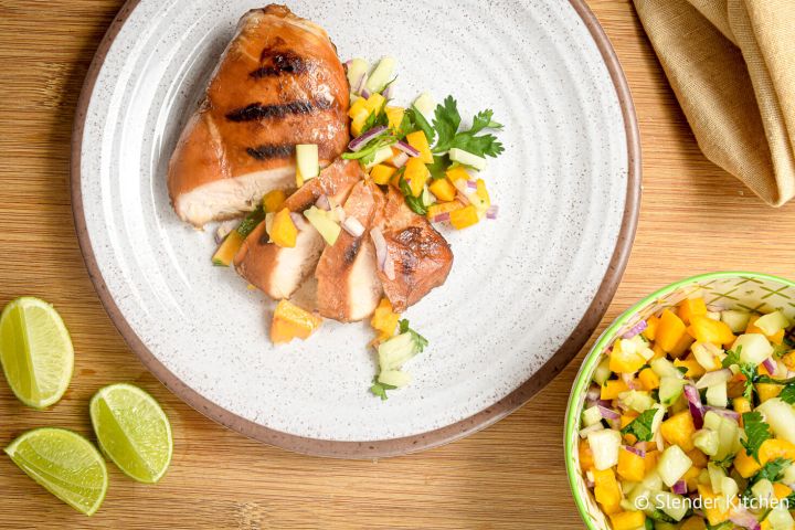 Grilled chicken with peach and cucumber salsa sliced on a plate.