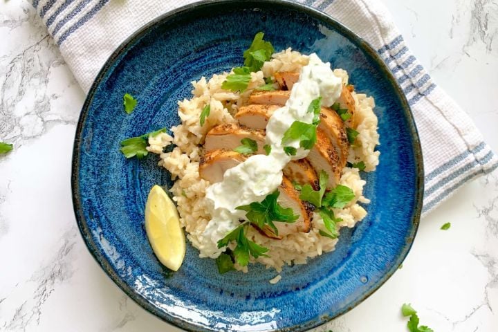 Grilled lemon chicken breast with tzatziki on a bed of rice. 