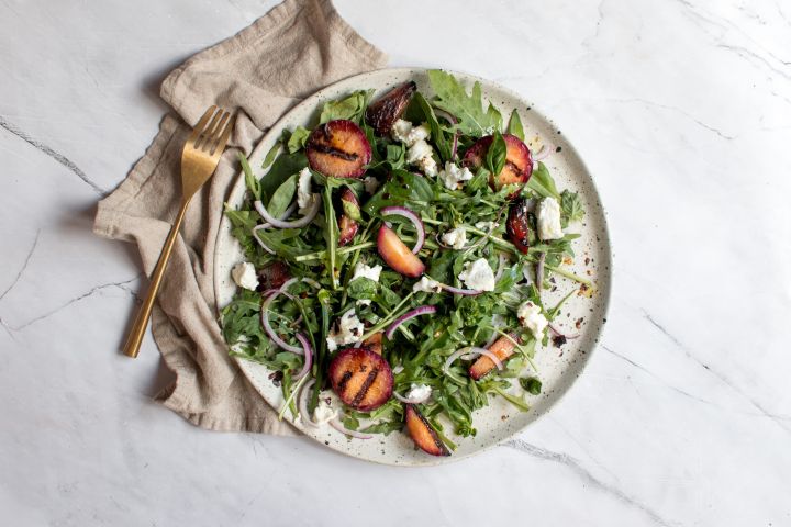 Grilled plum salad with arugula, grilled plums, red onions, goat cheese, and fresh herbs. 