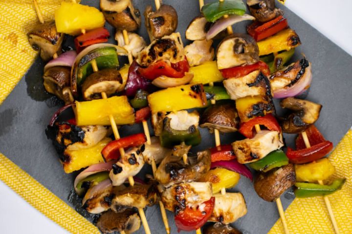 Hawaiian Chicken Kabobs with pineapple, mushrooms, and bell peppers on wooden skewers.