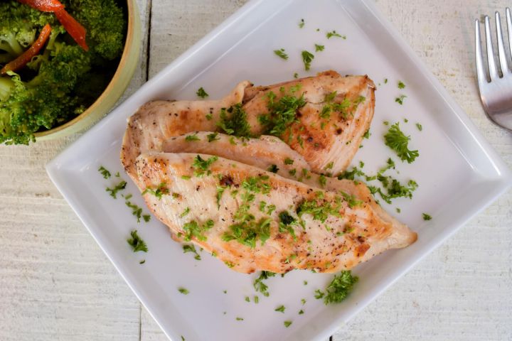 Herb chicken breast with an herb spice rub on a plate with fresh parsley.