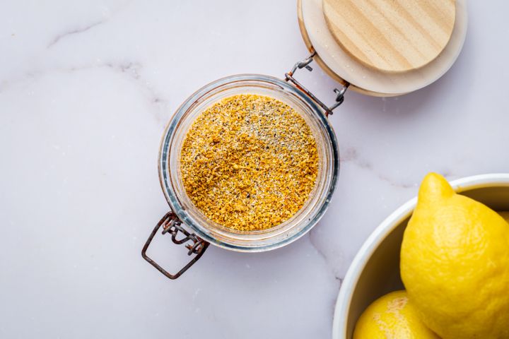 Homemade lemon pepper seasoning with dried lemon zest, black pepper, kosher salt, garlic powder, and onion powder in a glass jar.