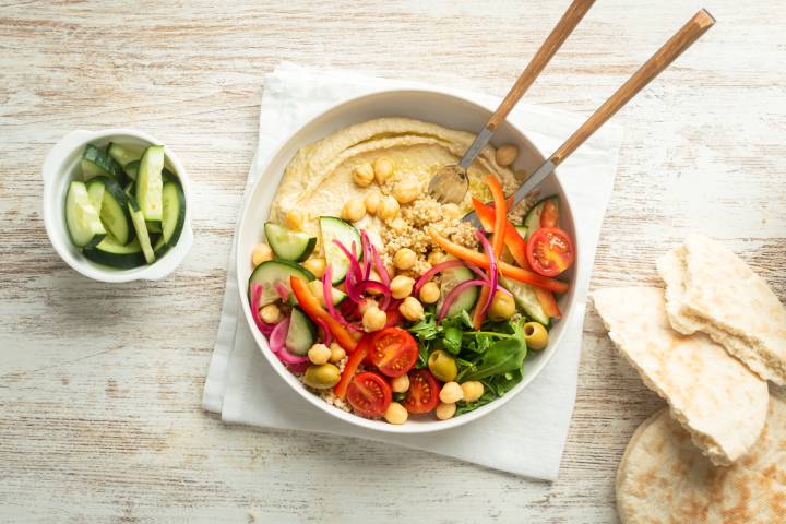 Hummus bowls with creamy hummus, quinoa, chickpeas, cucumbers, arugula, and red onions.