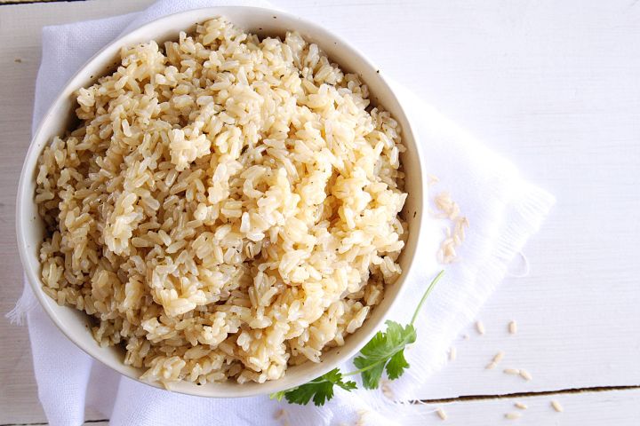 Instant pot brown rice in a bowl with small flecks of dried parsley.