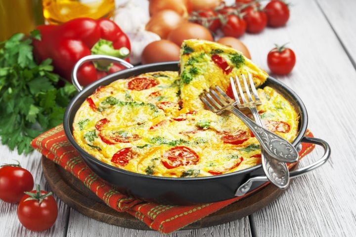 Italian breakfast frittata with arugula, roasted red peppers, eggs, and cheese in a baking dish.