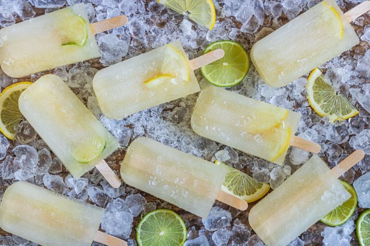 Lemon lime popsicles with fresh lemon and lime slices on a bed of ice.