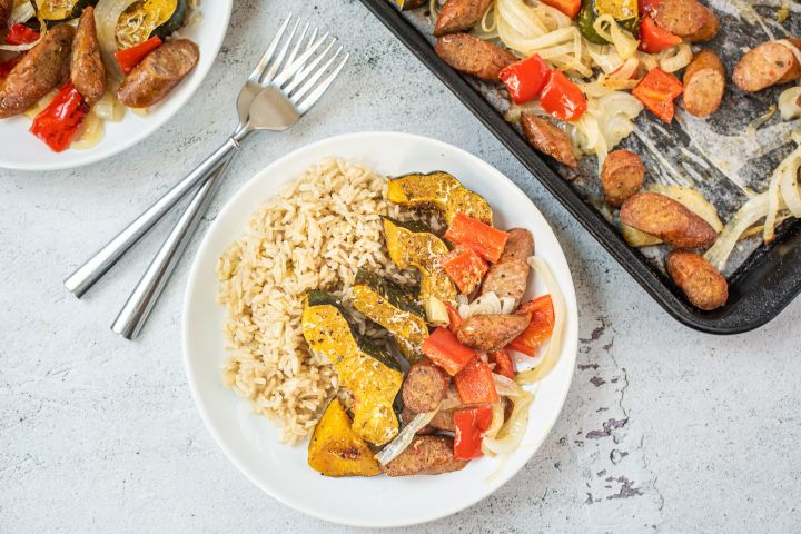 One pan sausage and acorn squash with bell peppers and onions on a plate with brown rice.