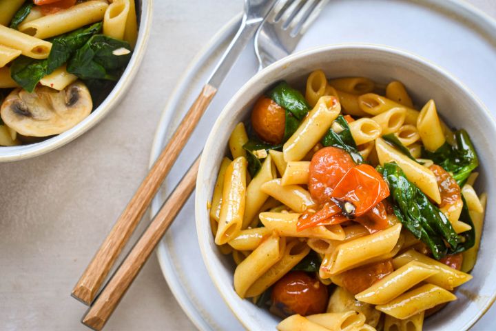 One Pot Tomato Basil Pasta in a bowl with mushrooms, spinach, and cherry tomatoes.