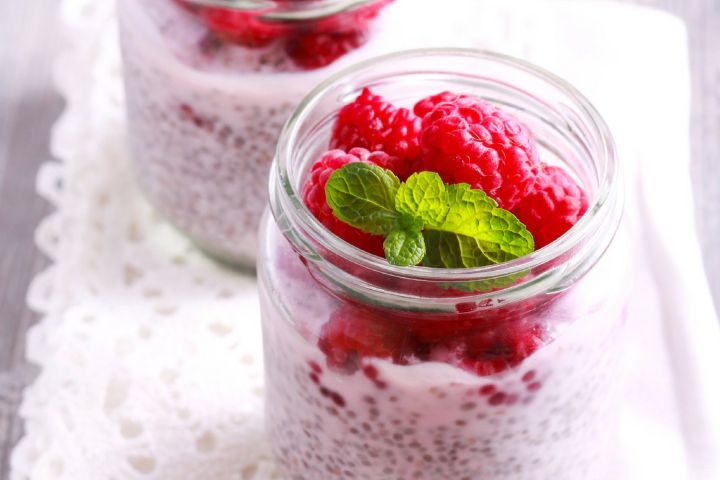 Low carb chia and flaxseed oatmeal in a glass jar with raspberries.