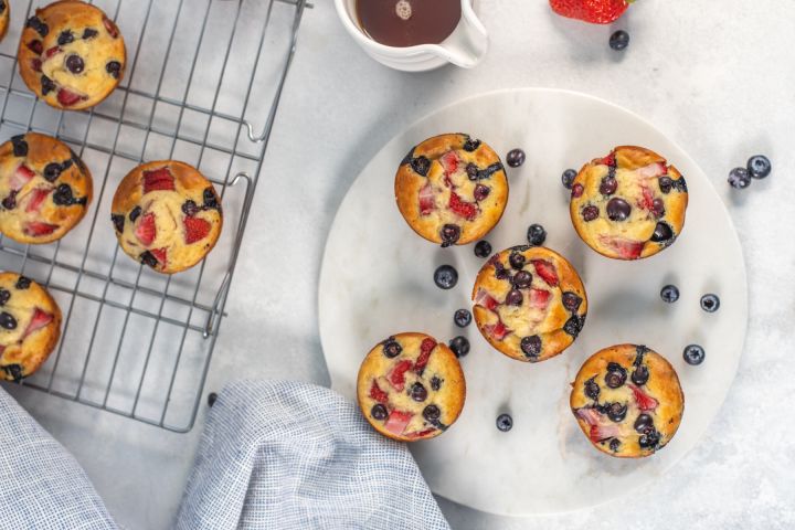 Pancake muffins with fresh fruit on a plate with a wire rack on the side.