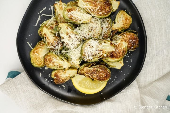 Parmesan Brussels Sprouts with lemon on a plate with a linen napkin.