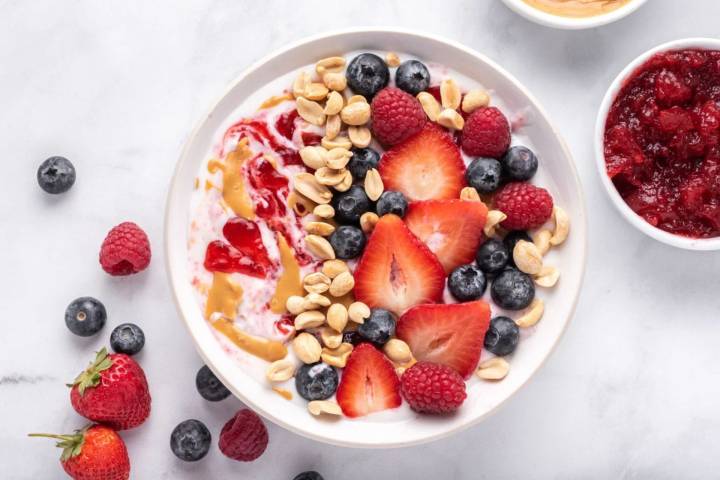 Peanut butter and jelly yogurt bowl with peanut butter, strawberry jelly, peanuts, and fresh fruit.